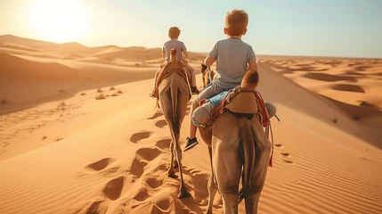 Selbstklebende Fototapeten smiling children riding their camels traveling in the UAE desert in a sunny morning © Salsabila Ariadina