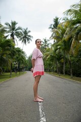 Young caucasian woman standing alone on the road in a tropical setting