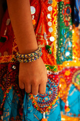 A girl child wearing a colorful outfit and a bracelet