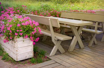 Sunny summer garden with wooden furniture and blooming flowers