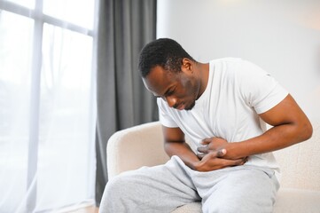African american guy having stomach ache after eating touching aching stomach suffering from pain...
