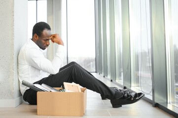 Sad african american businessman sitting on office building, man in business suit bankrupt fired...