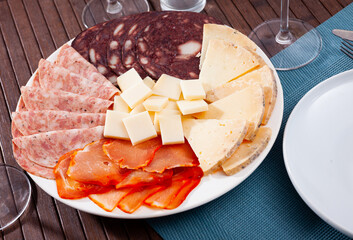 Slices of Spanish cheeses, dry-cured loin, salami and morcilla on plate. Traditional meat delicacies