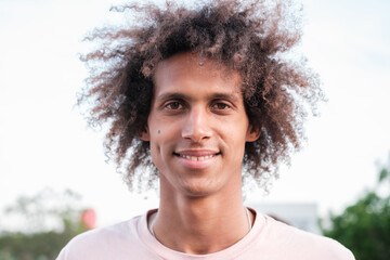 Young man with curly hair smiling outdoors close-up. Concept: lifestyle, fun