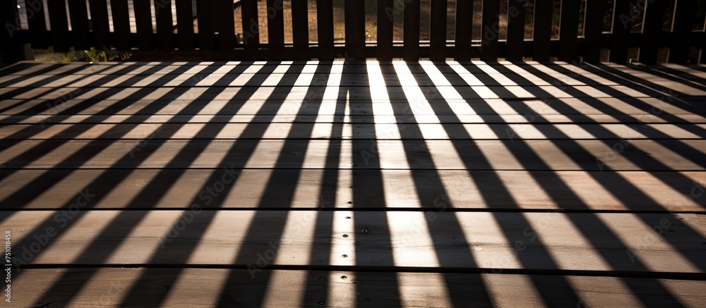 Poster the shadow of a fence is cast on the ground, creating a striking and abstract pattern. the wooden de