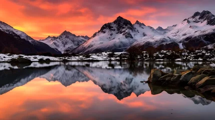 Schilderijen op glas Panoramic view of snow capped mountains reflected in a lake at sunset © Iman