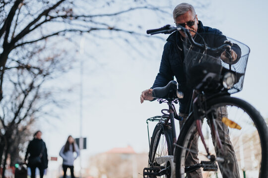 An elderly gentleman confidently rides his bike, enjoying leisure time outdoors. A concept of active senior lifestyle and urban commuting. © qunica.com