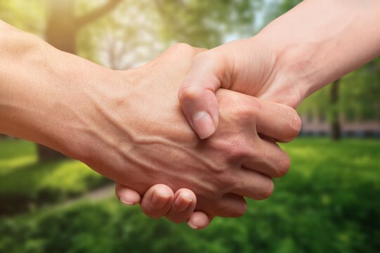 Two people shaking hands on outdoor background