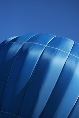 The blue hot air balloon with red, yellow, grey stripes is rising up into the sky. Colourful hot...
