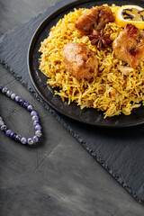 Spicy Chicken Biryani with Lemon on Black Plate, Ramadan Food Concept, Copy Space
