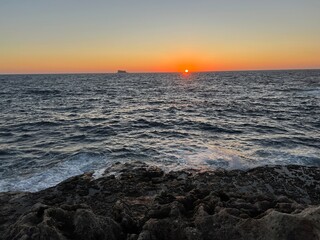 Sunset on the Mediterranean Sea with a far away seen island in the distance at Malta 