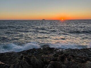 Sunset on the Mediterranean Sea with a far away seen island in the distance at Malta 