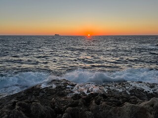 Sunset on the Mediterranean Sea with a far away seen island in the distance at Malta 