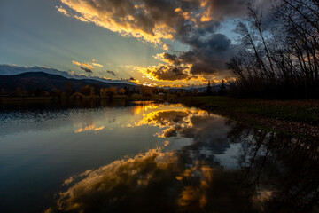 Fototapeta na wymiar Beautiful bright sunset reflection in calm lake water in fall season