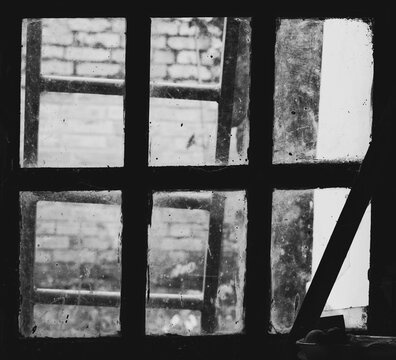 Behind the closed blurred window stands an old ladder. - Powered by Adobe