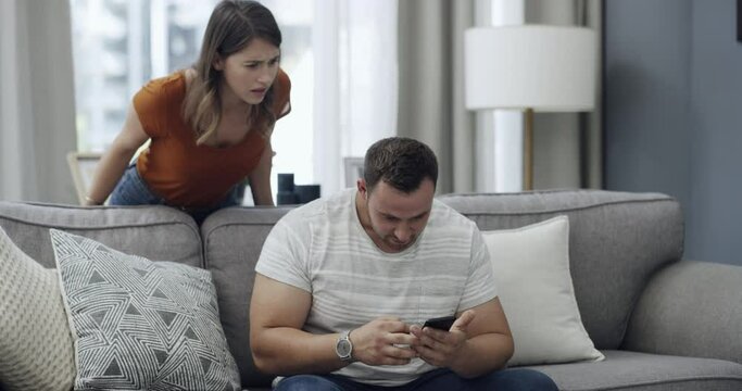 Infidelity, couple and caught cheating on phone with fight, conflict or argument about social media. Online, divorce or breakup with young man and woman on sofa in home living room for communication