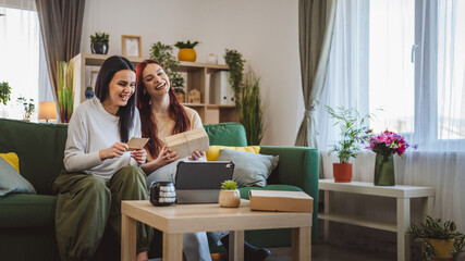 two women sisters or friends open presents in front of digital tablet