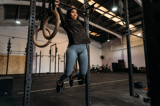 Muslim woman exercising on bar in gym