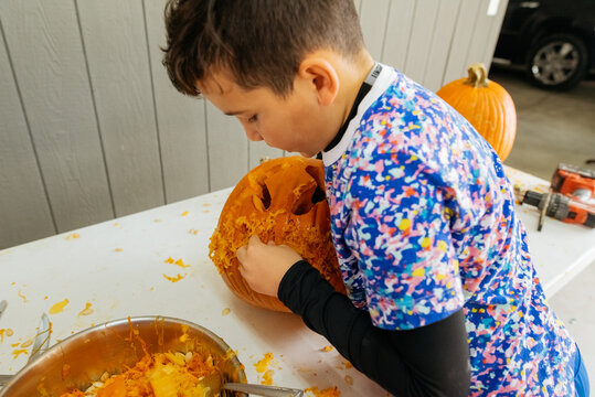 A child busy carving a pumpkin. 