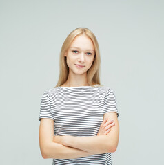 Obraz premium young woman with long blond hair dressed casual posing with crossed arms over grey background