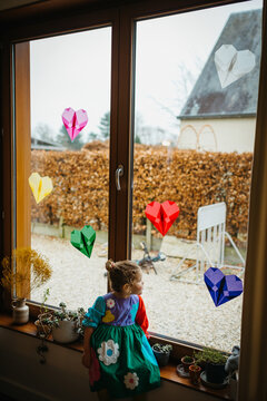 Girl with flower dress standing in front of window with handmade decor