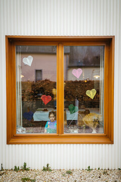 Birthday girl by the window. Kite paper hearts for decoration.