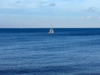 Obraz premium View of the sea and white sailboat on the horizon from the balcony on the promenade by the sea at Sliema Malta
