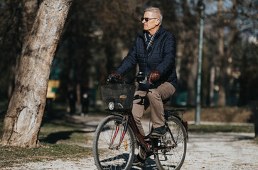 Obraz premium Senior man enjoying a leisurely bike ride in a peaceful park setting.