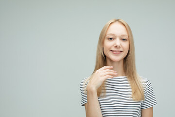 young woman with blond hair smiling isolated over light grey color background