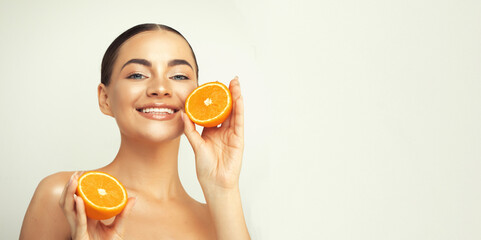 lovely young woman standing isolated over white background, showing slices of an orange