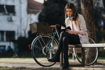 Serene scene of a focused female enjoying writing in her notebook, seated on a wooden bench...