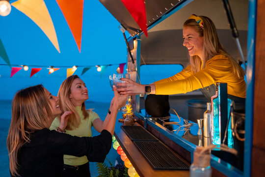 Friendly bartender giving alcohol to girlfriends