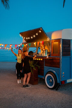 Girlfriends making order in food truck on beach