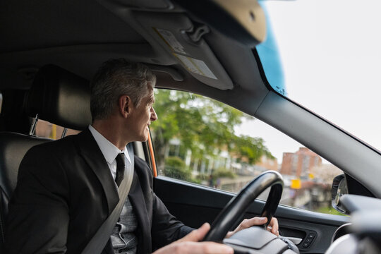 Man driving car wearing business suit.