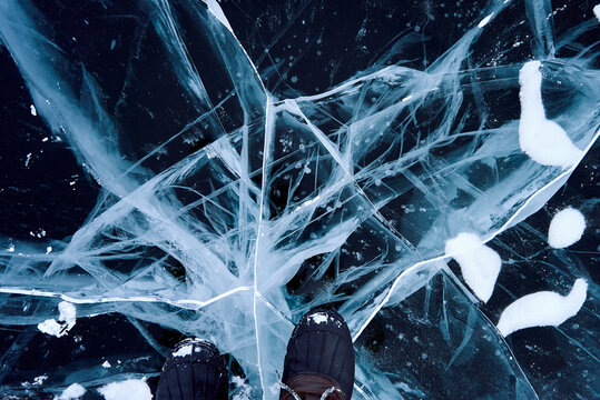 Feet standing on transparent sea ice