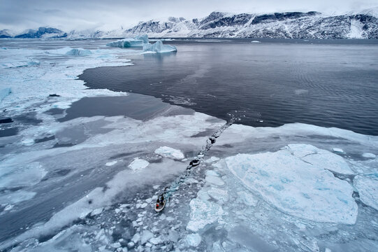 Indigenous Inuit boat fishing in Arctic sea ice