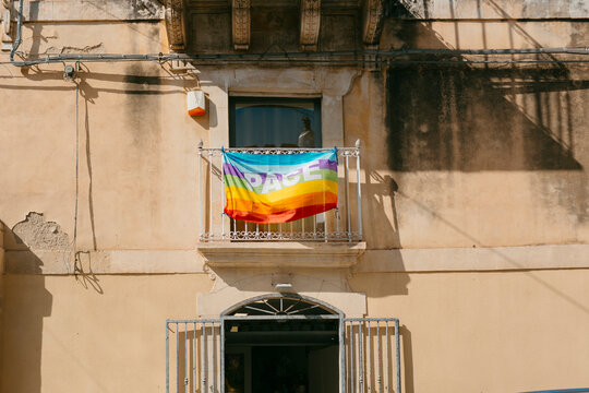 Rainbow flag hanging from a balcony in an old Italian city