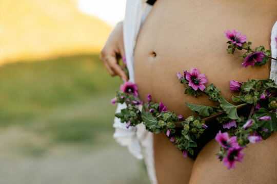 A Woman Wraps Flower around her Pregnant Belly