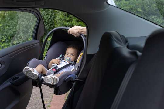 father putting baby in car seat and fasten seat belt