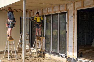 Workers on construction site attaching cladding to roof of home