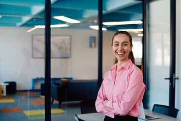 Portrait of a business woman in a creative open space coworking startup office with crossed arms. Successful businesswoman standing in office with copyspace. Associates work in the background