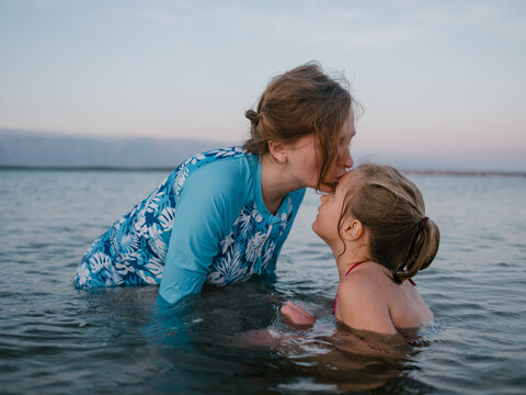 Mom kissing daughter on the forehead in the sea