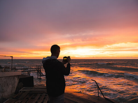 Mens silhouette take a picture sunrise sea and dramatic sky and clouds