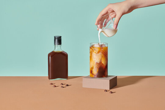 Iced coffee in a tall glass with cream and ice cubes