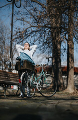 Woman relaxing on park bench with bicycle on a sunny day enjoying nature.
