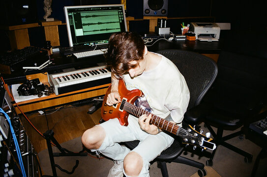 adult man playing guitar in recording room