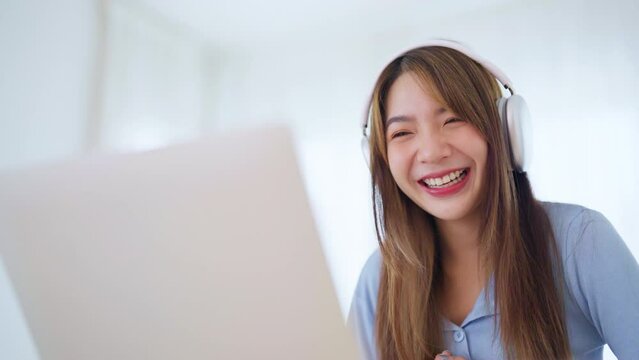 Young asian woman wearing headset working on computer laptop at house. Work at home, Video conference, Video call, Student learning online class, Homeschooling