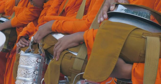 close up of a woman offering food to monks is known as "tak bat. It is also a way for monks to receive the support they need to live a monastic life.