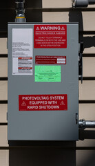 Stickers required by regulations adorn the rapid shutdown box of a residential home's photovoltaic...
