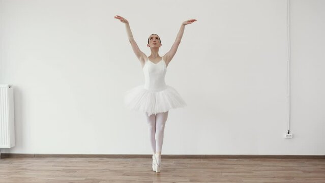 Beautiful young female ballet dancer bending over effortless on stage with harmony, body shape movement, fitness flexibility indoors. Woman in tutu motion, balance flexibility concept, lifestyle.